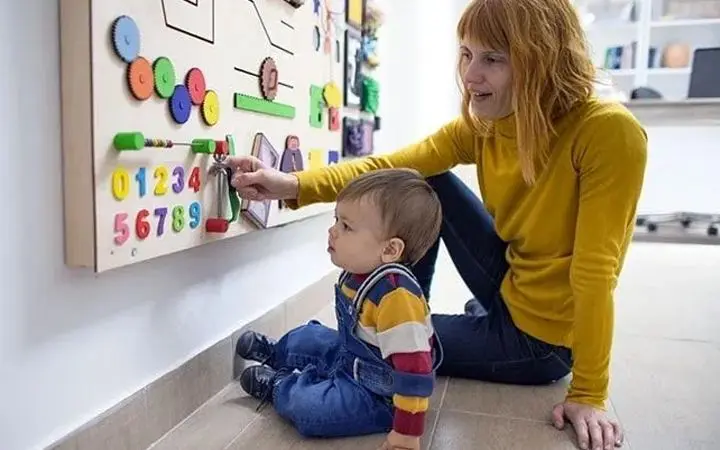 A woman teaching a small kid with the help of a 3d board