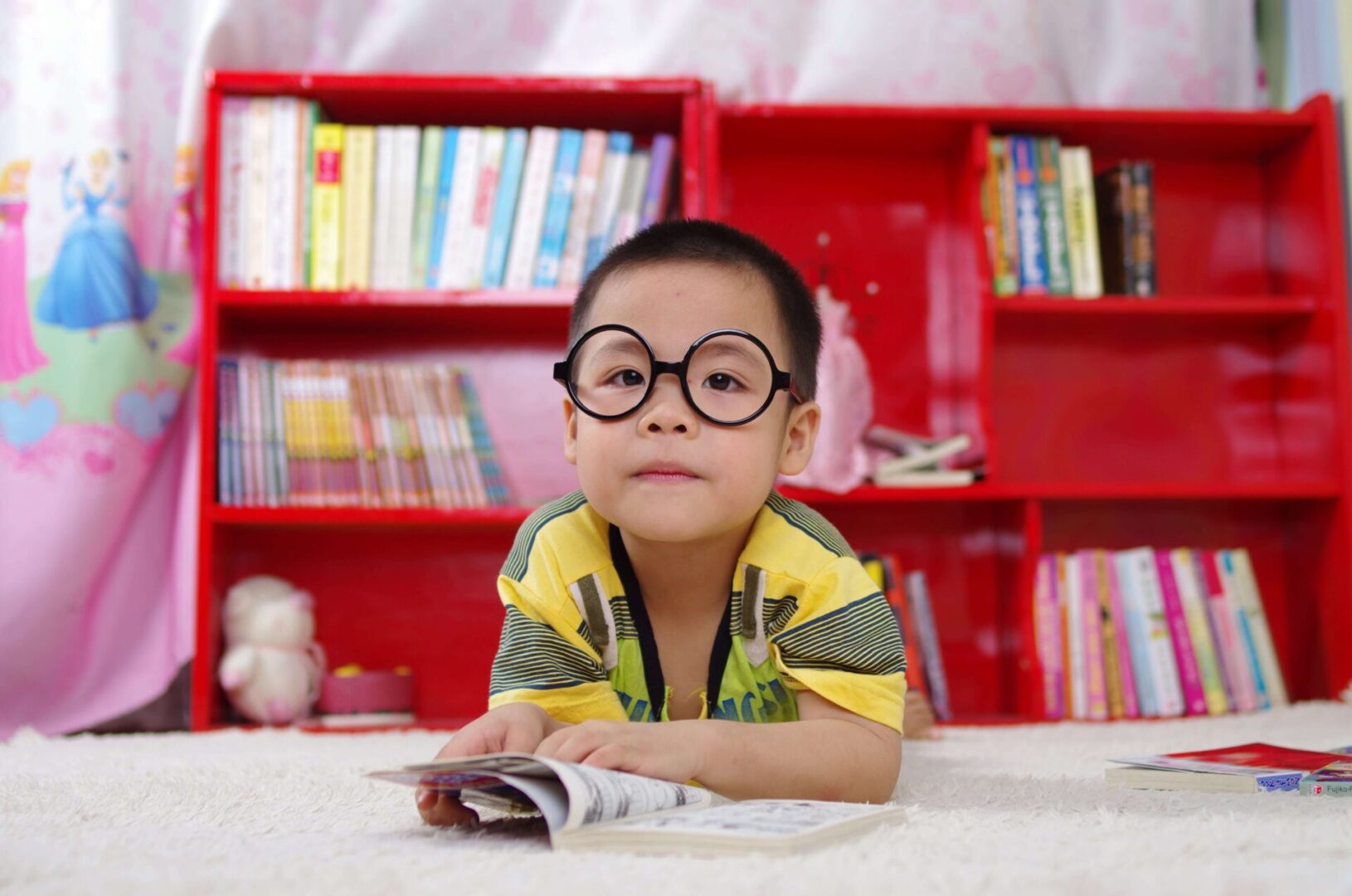 A closeup shot of a small boy wearing googles reading a book